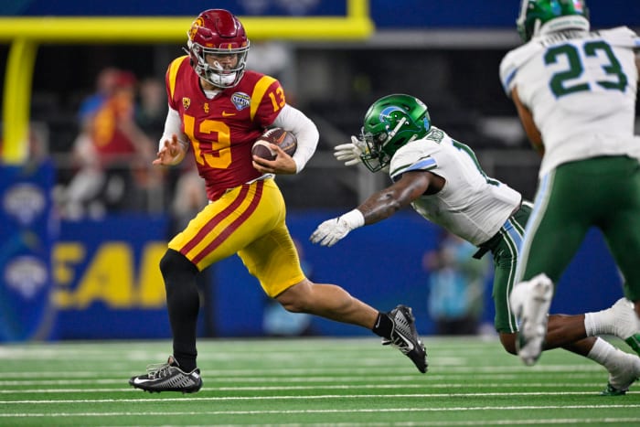 Caleb Williams runs with the ball as a Tulane defender reaches for him